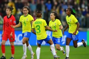 Imagem horizontal 16:9 representando a seleção feminina de futebol goleando a Coreia do Sul na estreia da Fifa Series, surpreendendo o mundo.